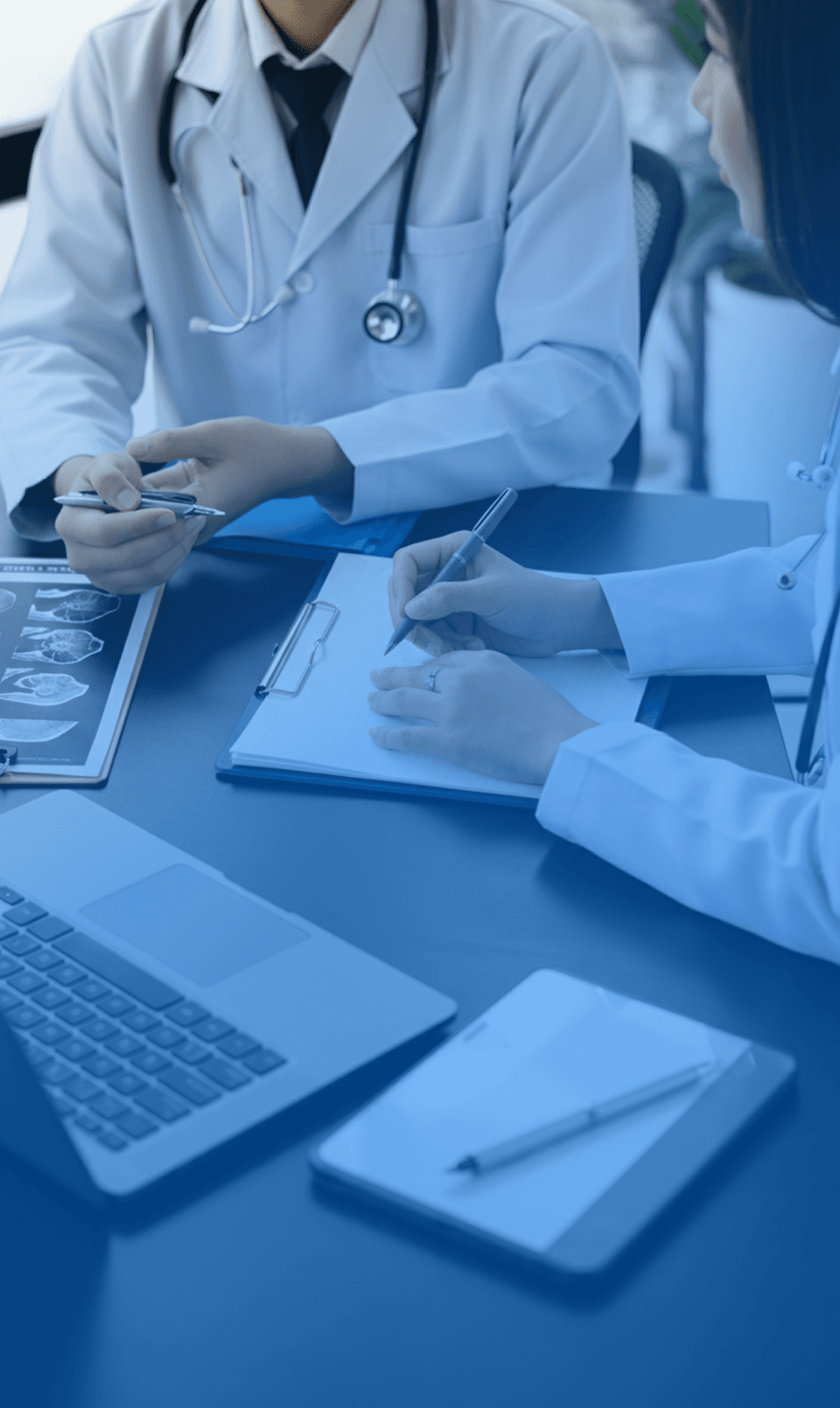 Doctors talking each other and analysing some exams in one table with laptop